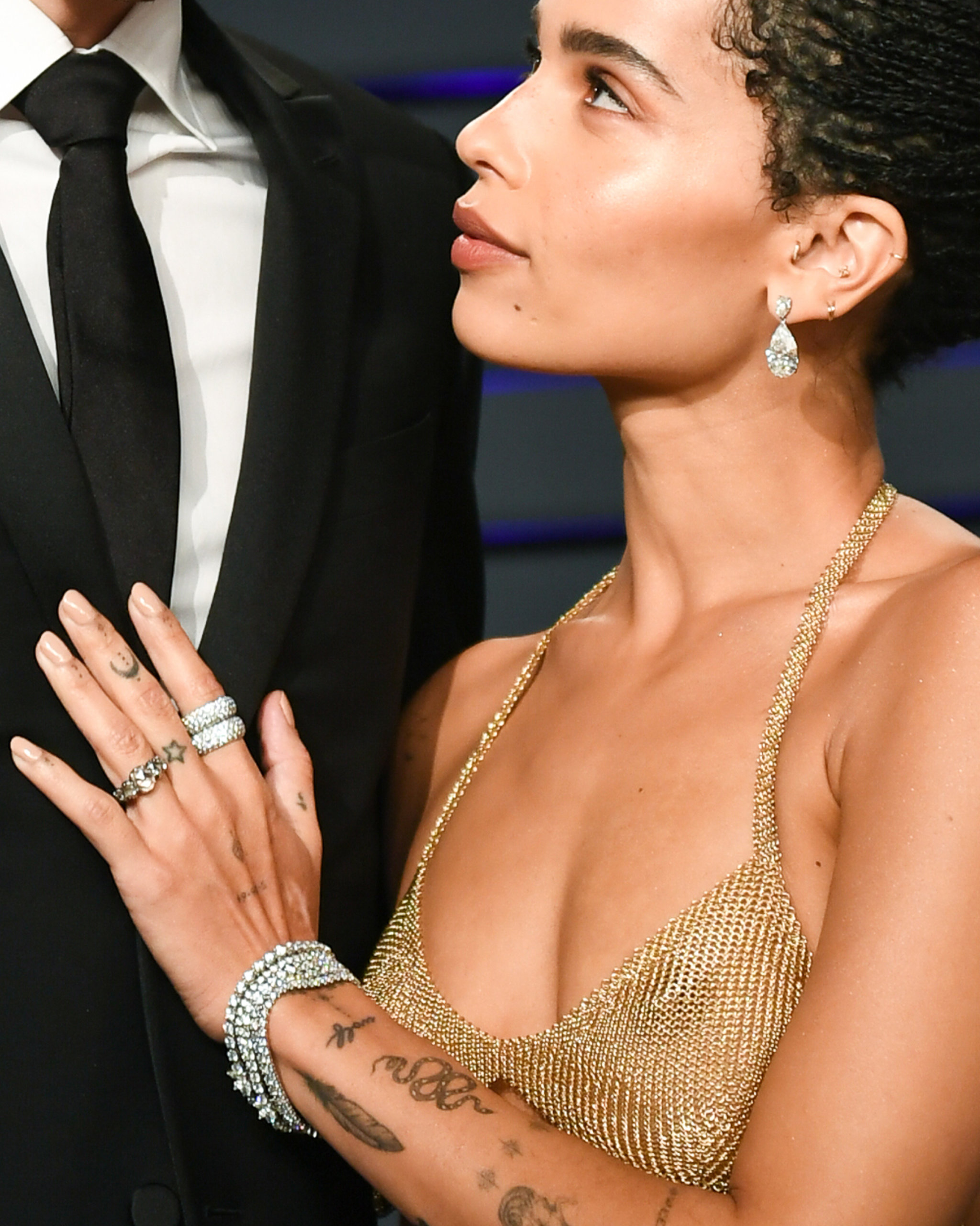 Zoë Kravitz wearing pear shaped diamond earrings, a stack of pave diamond rings and diamond bangle bracelets