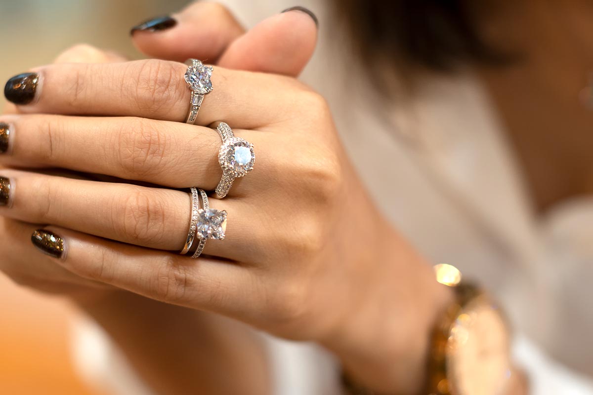 Heart shaped, round cut, princess cut diamond engagement rings and one pave diamond band on a woman's hand