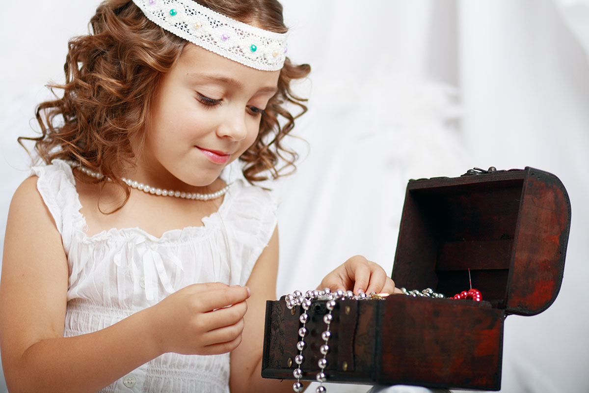 A small girl going through a jewellery box