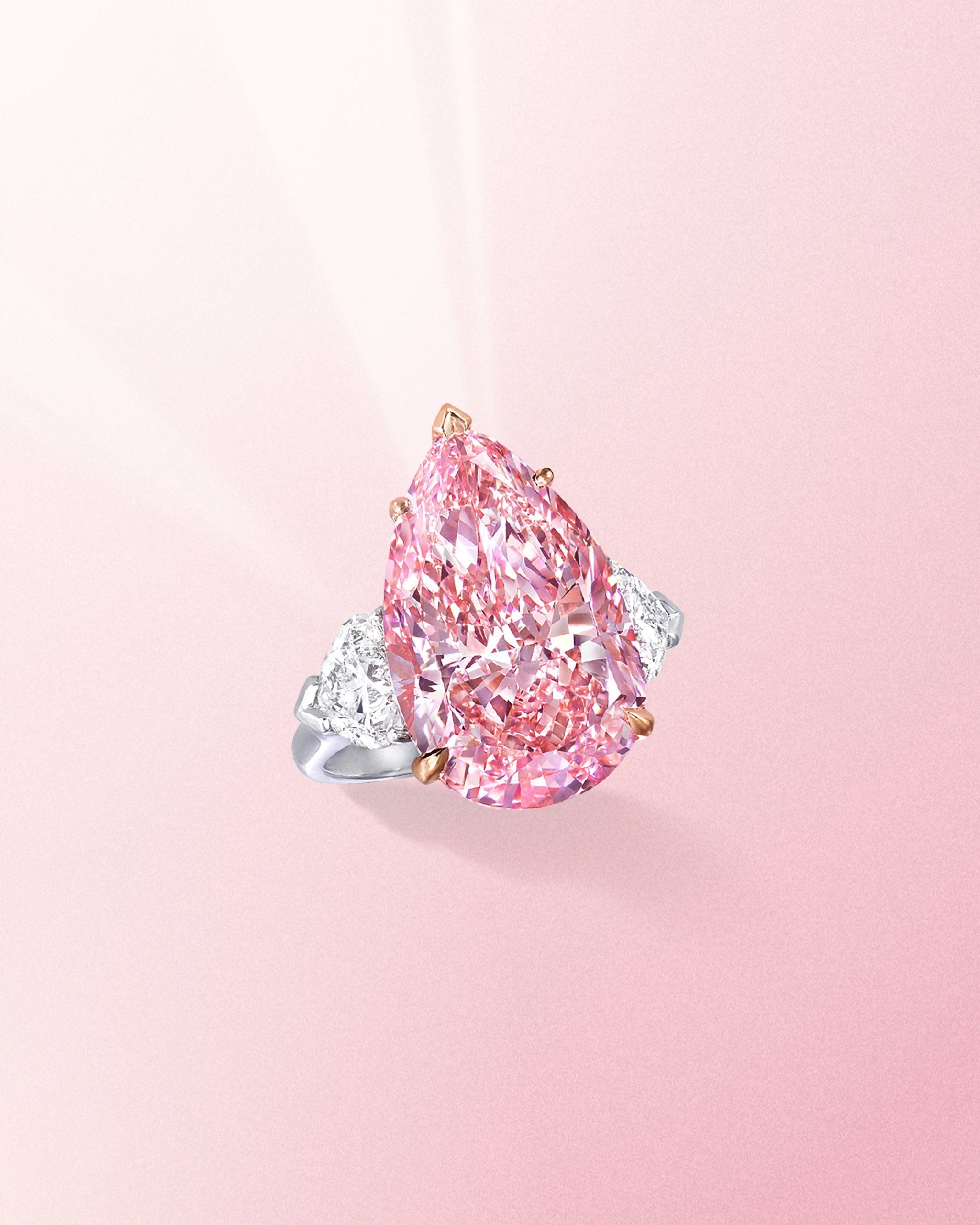 Fancy vivid pear shaped pink diamond ring with side white diamonds on a platinum band from Graff