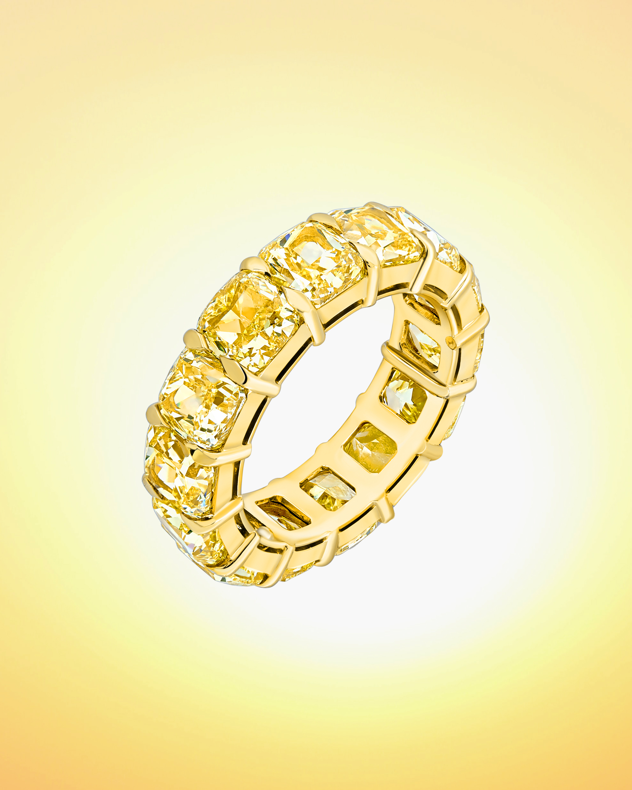 Fancy cut yellow diamond ring in the eternity ring style on a yellow gold band by David Morris
