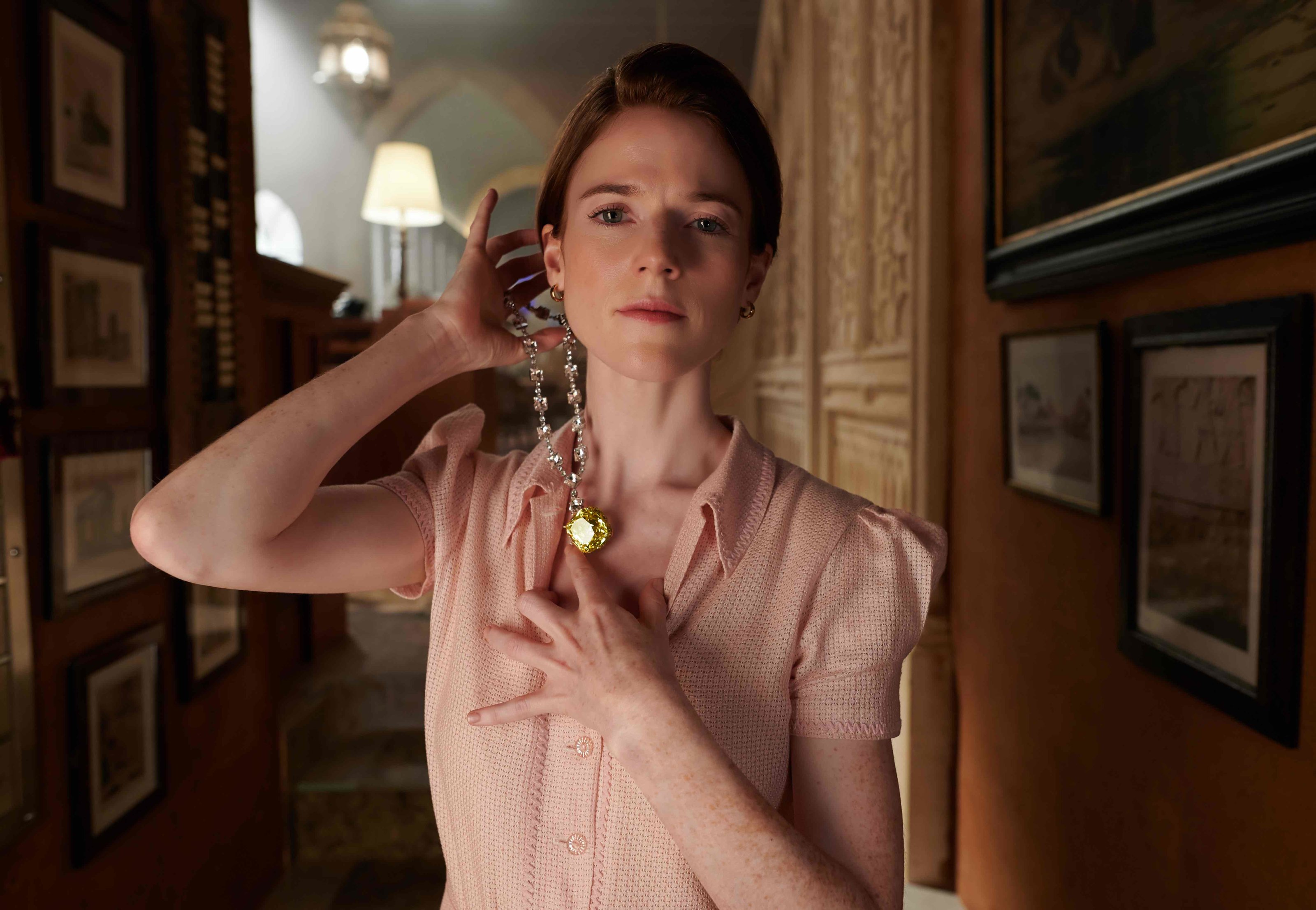 Rose Leslie trying on a diamond necklace with a 128-carat fancy yellow diamond by Tiffany in the Death on The Nile movie