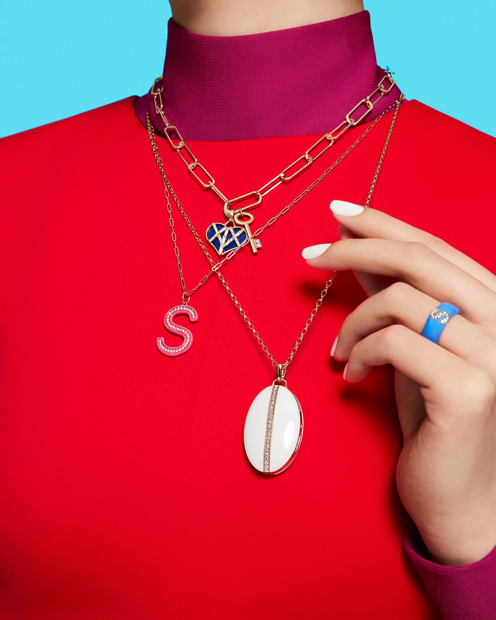 Blue enamel heart necklace on gold chain and locket by Michelle Fantaci, pink "S" diamond pendant necklace by Stephanie Gottlieb, white oval pendant necklace with diamonds Monica Rich Kosann