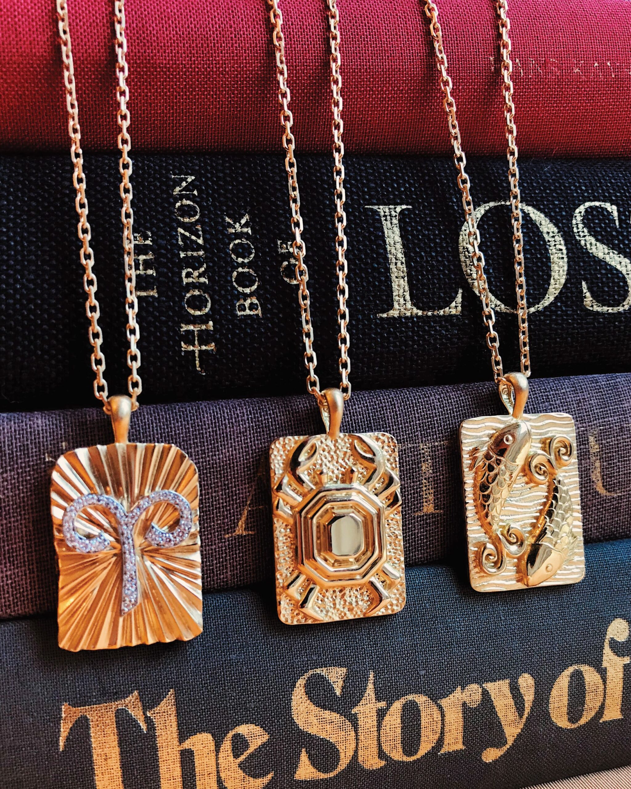 Zodiac necklaces from David Webb featuring carved gold and studded diamond zodiac pendants