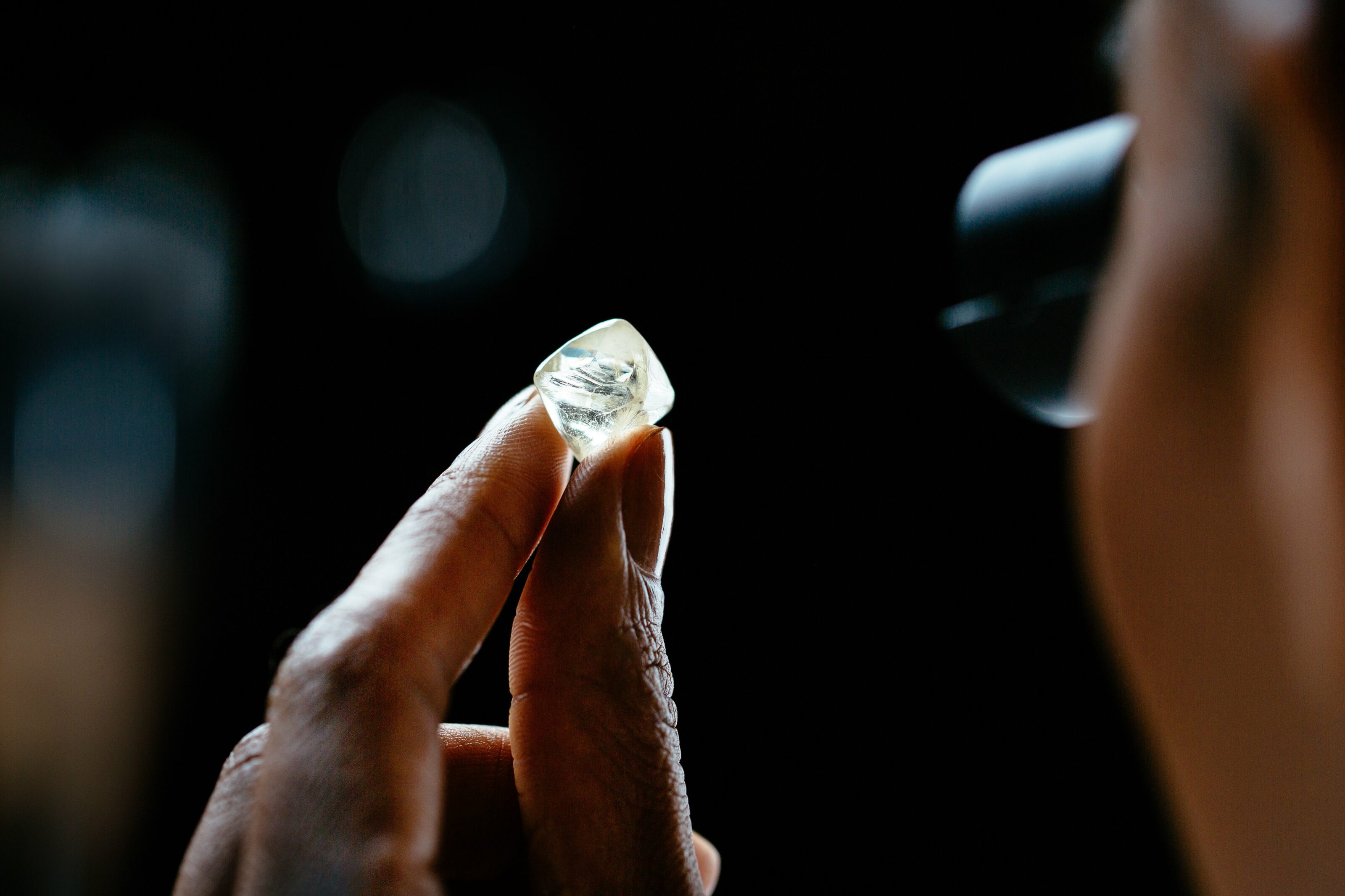Examining natural rough diamond through a loupe 