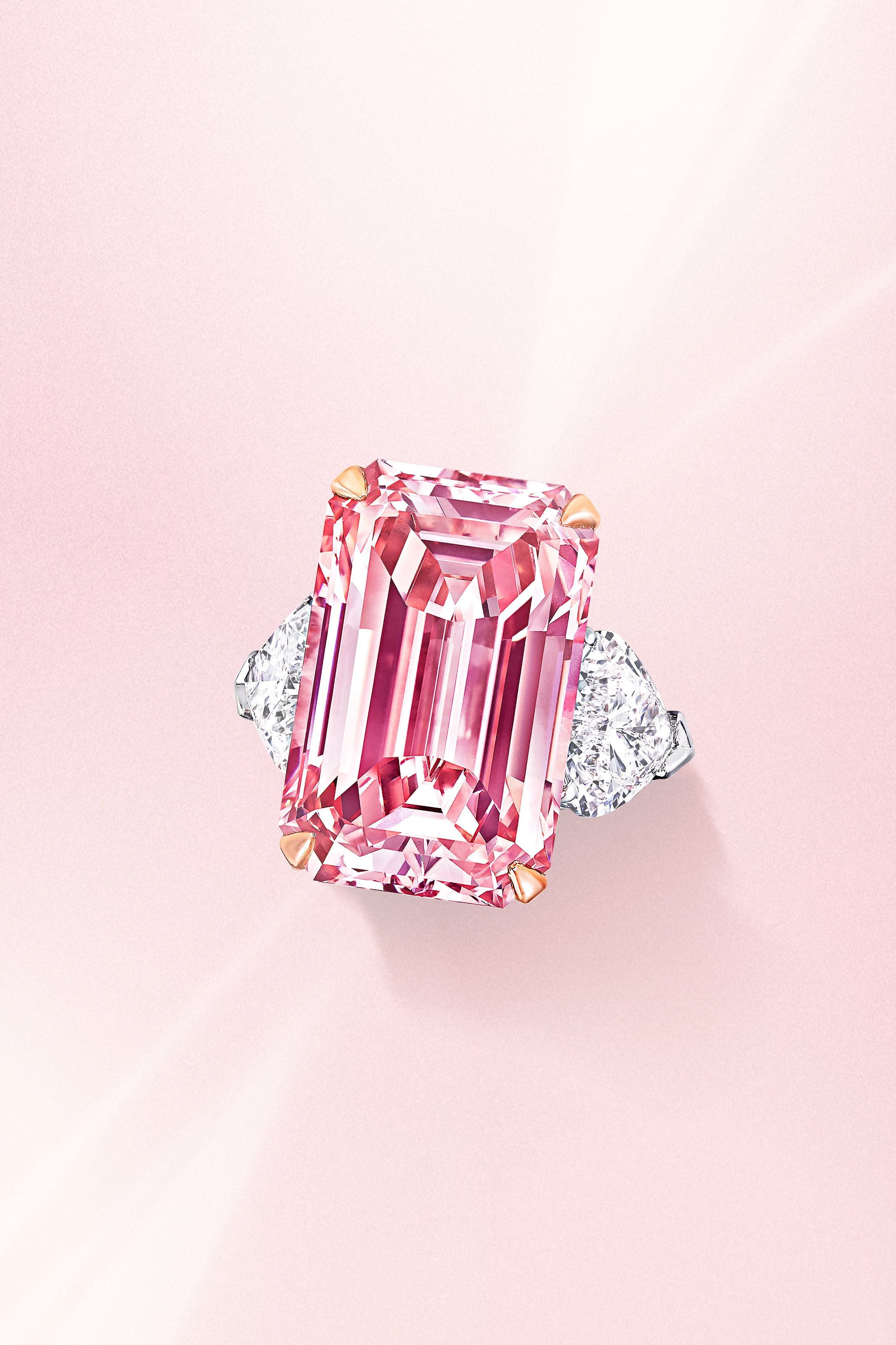 Rectangular emerald cut pink diamond ring with side white diamonds on a platinum band from Graff