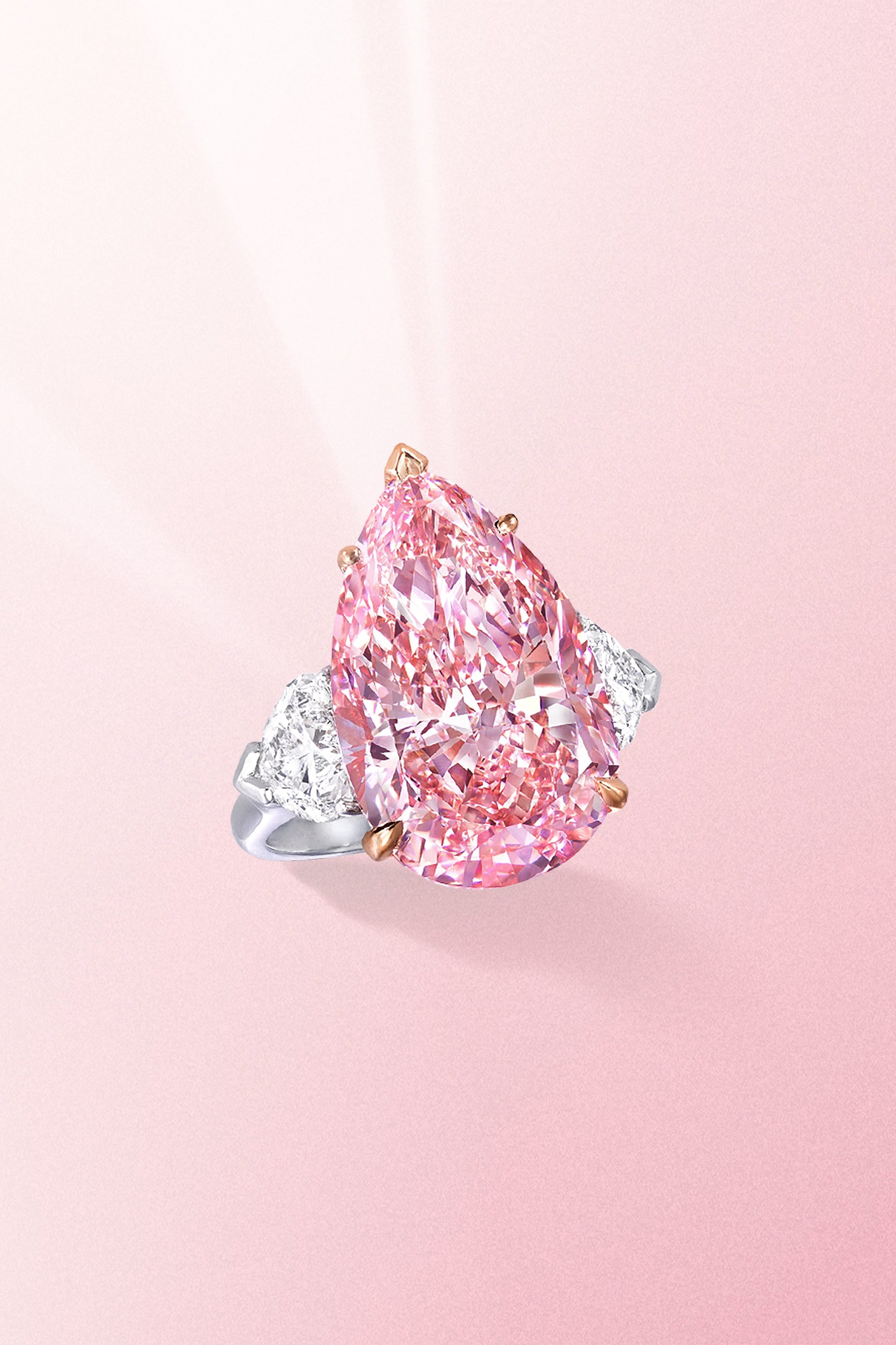 Fancy vivid pear shaped pink diamond ring with side white diamonds on a platinum band from Graff