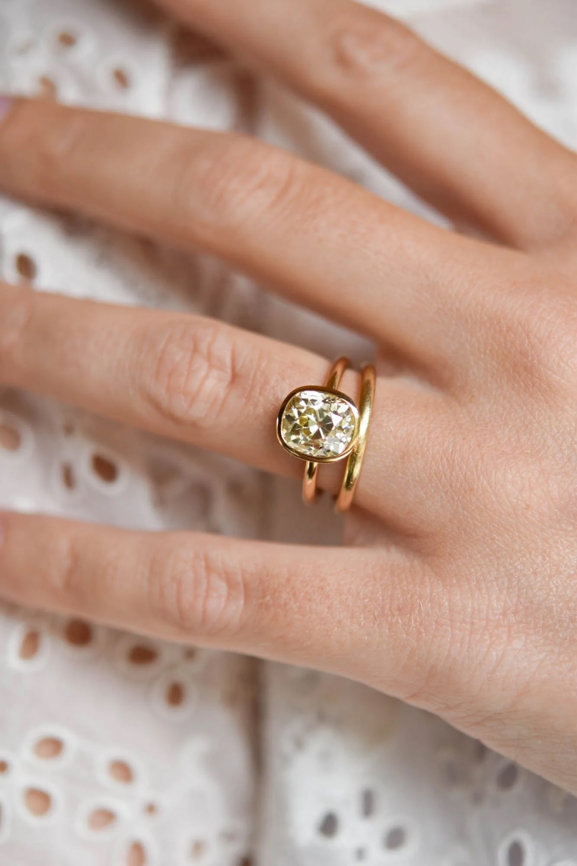 Old mine-cut diamond in a yellow gold bezel set solitaire engagement ring