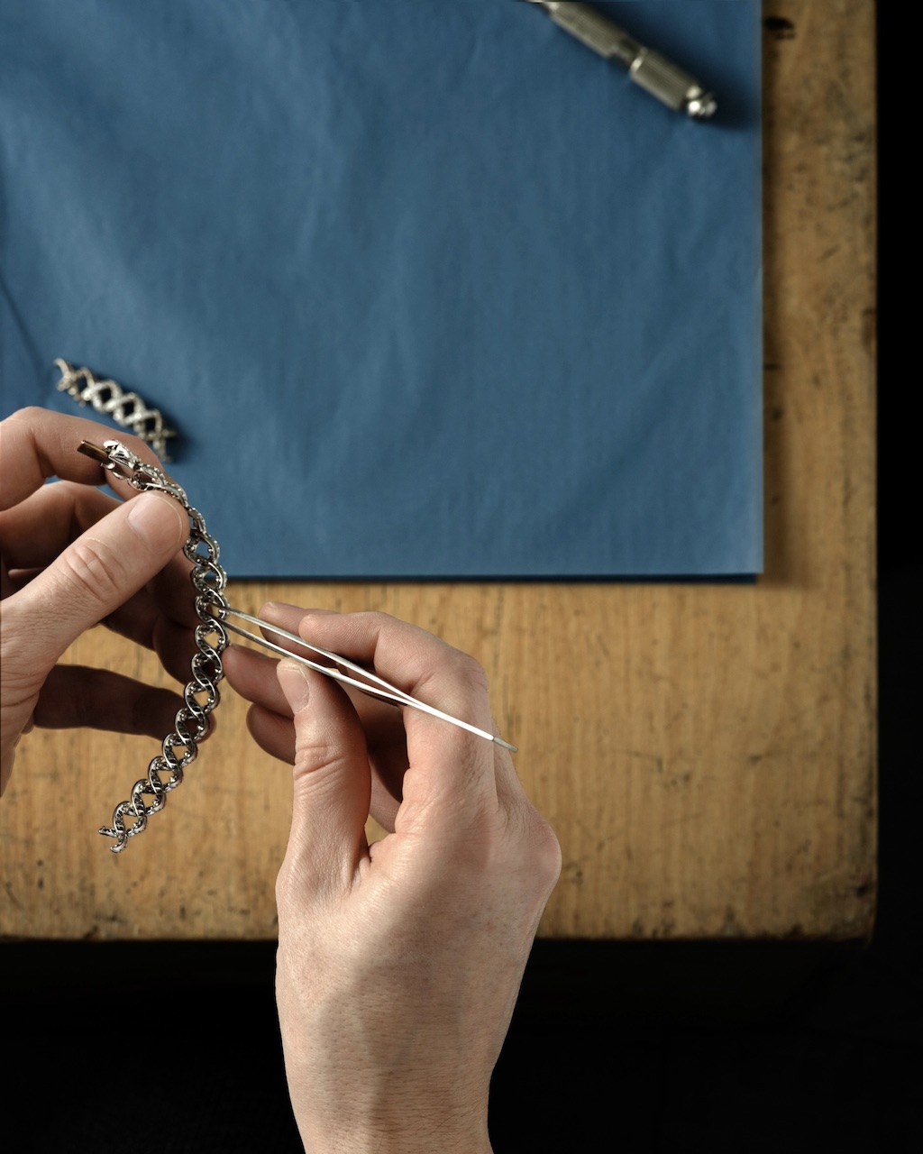 Handcrafting the Diamond Jasmine necklace from Blue Book 2026: Hidden Garden. An artisan carefully fits a diamond in a partially set casting component.