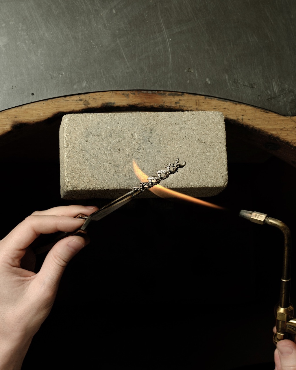 Handcrafting the Diamond Jasmine necklace from Blue Book 2026: Hidden Garden. An artisan solders a casting component.