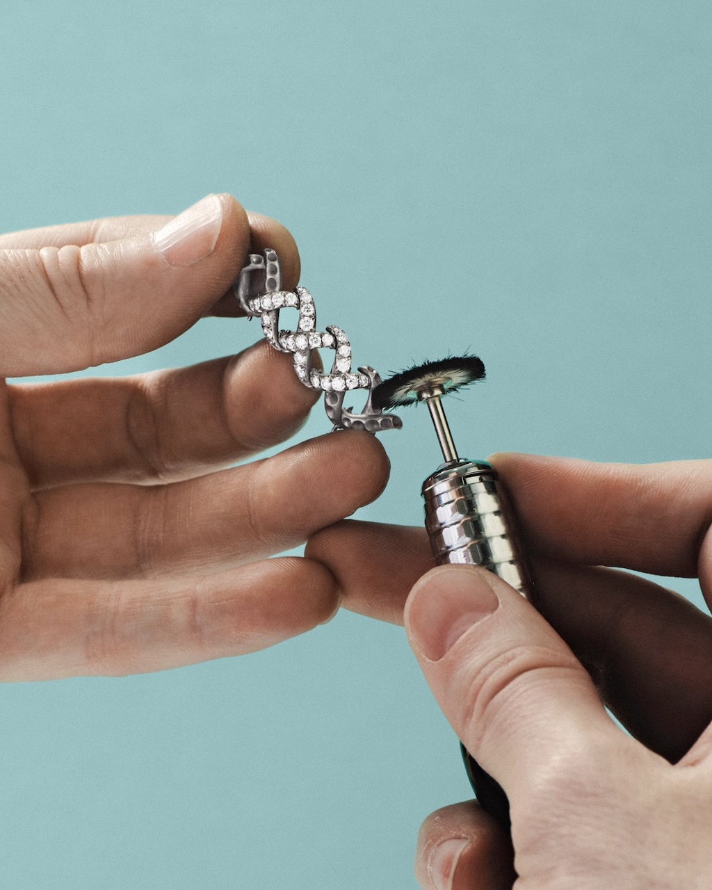 Handcrafting the Diamond Jasmine necklace from Blue Book 2026: Hidden Garden. An artisan carefully polishes a partially set necklace component.