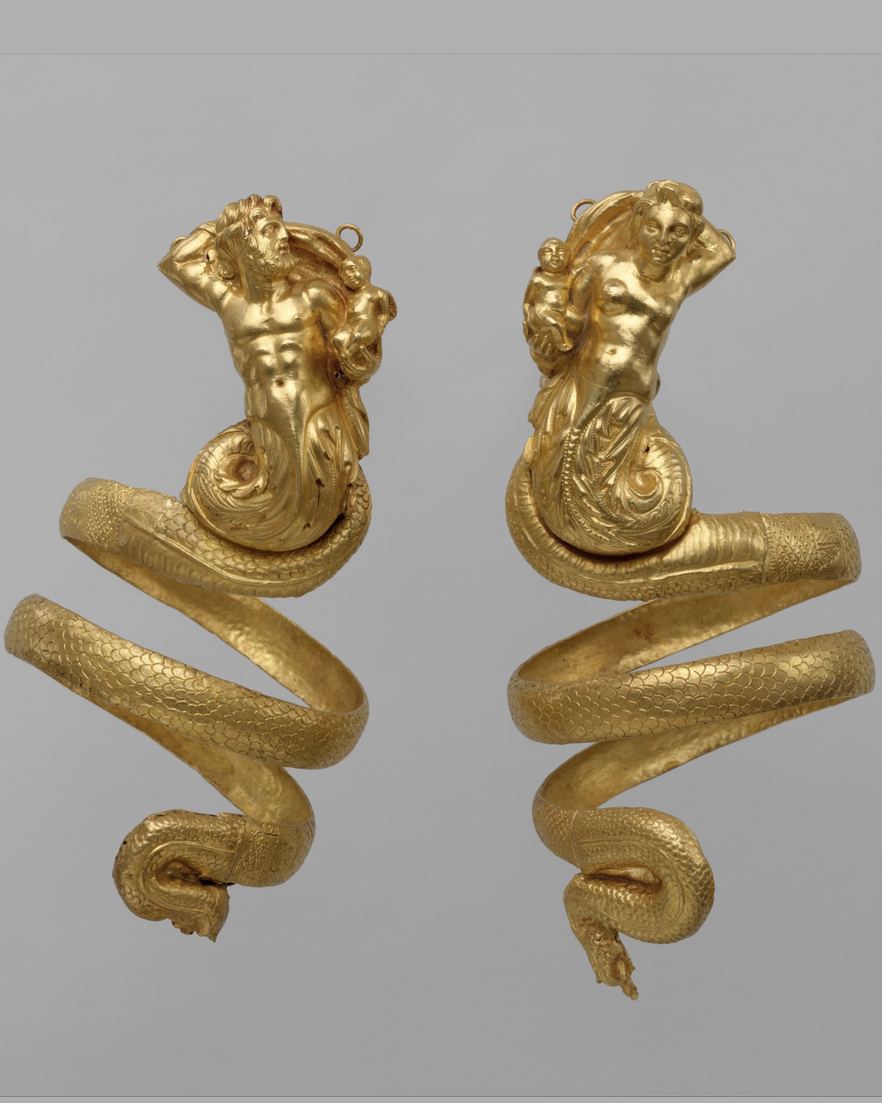 Neoclassical Ancient Greek jewelry Pair of Gold Serpentine Armbands representing male and female tritons, holding a small winged Eros. Crica ca. 200 BCE, Hellenistic Period, Greece. (Courtesy of the Metropolitan Museum of Art)